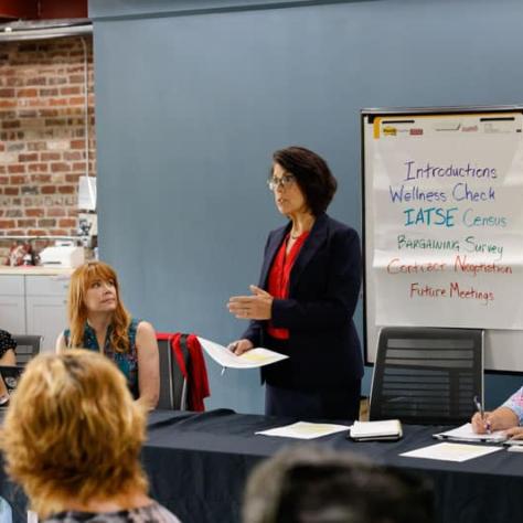 Woman standing behind a table presenting. 