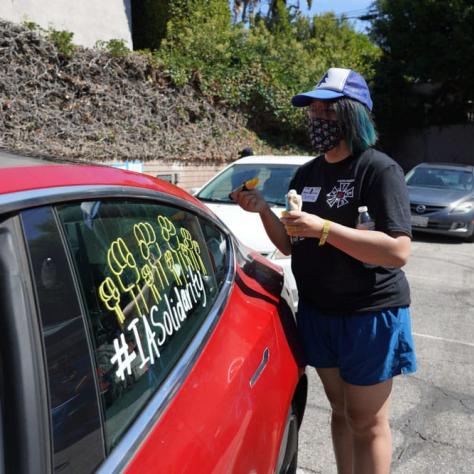 Woman writing on car window. 