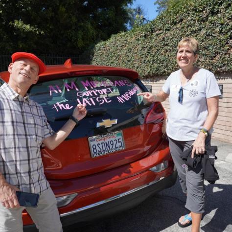 People posing with car window drawing. 