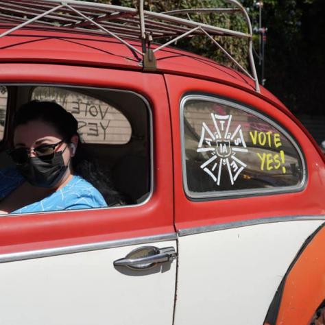 Person posing in car with message on window. 