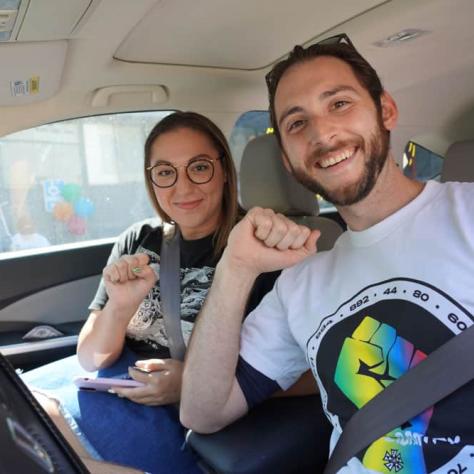 Two people posing in their car with fists. 