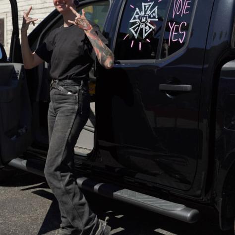 Person posing outside of car with message on window. 