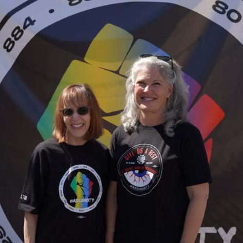 Two people posing for a photo in front of a backdrop. 