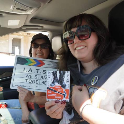 People posing in car with signs. 