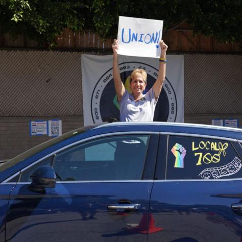 Car and person posing with a sign. 