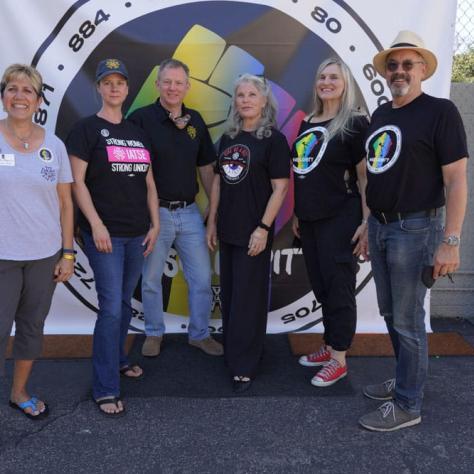 Group of people posing in front of backdrop. 