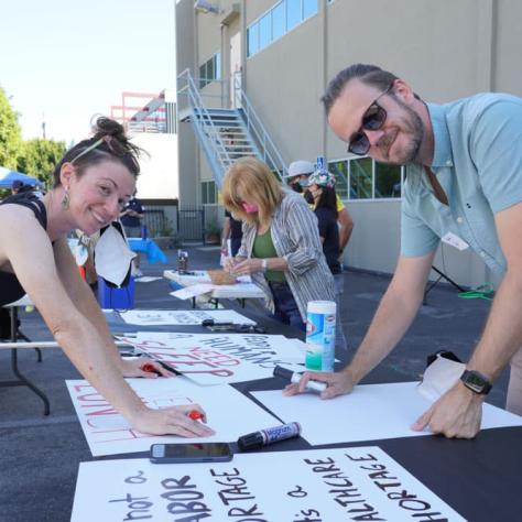 Two people posing while making signs. 