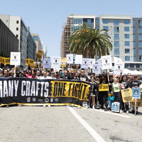 Group photo of people holding banner at rally. 