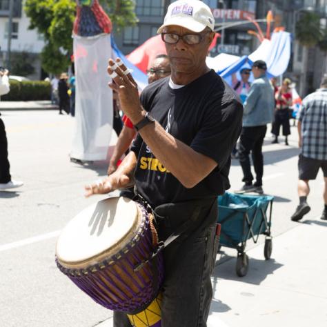 Man playing drums and marching in rally. 