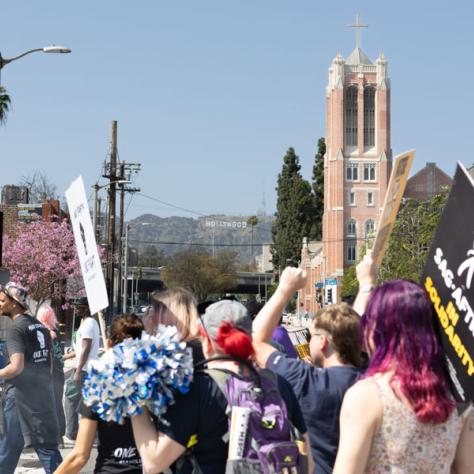 People marching with signs at rally.