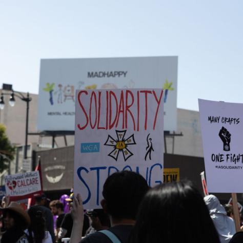 People marching with signs at rally.