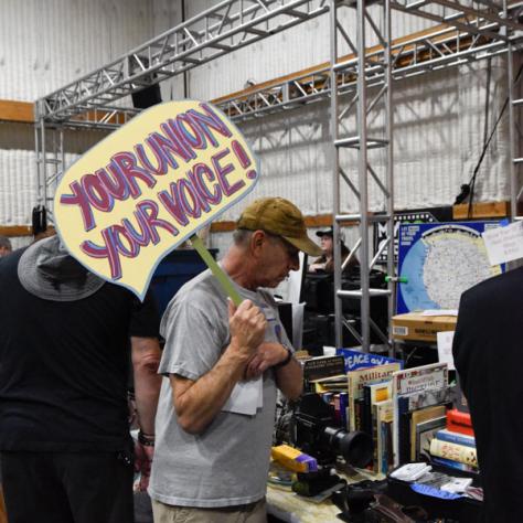 Man holding sign shopping at yard sale. 