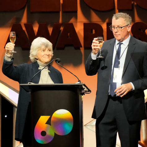 People at podium on stage raising glasses. 