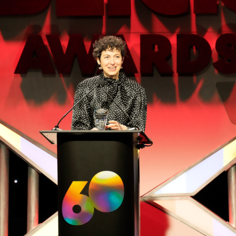 Woman standing at podium talking.