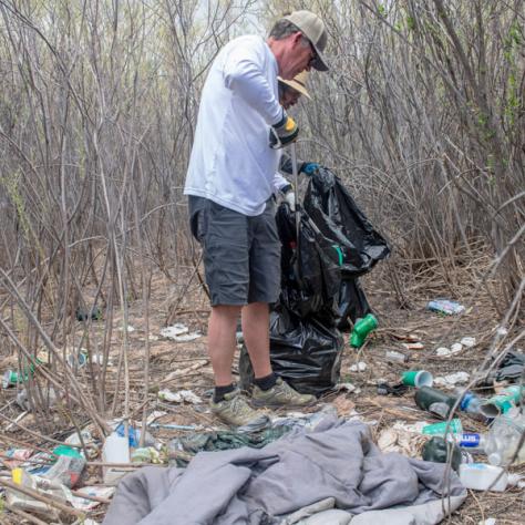 Person picking up trash outside. 