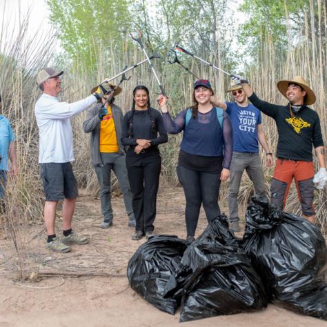 Group of people posing with trash grabbers and trash bags. 