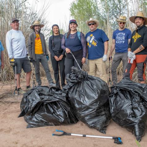 Group of people posing with full trash bags. 