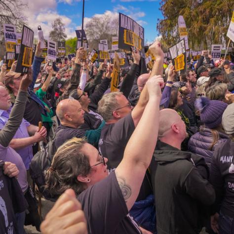 Crowd of people holding fists up at rally. 