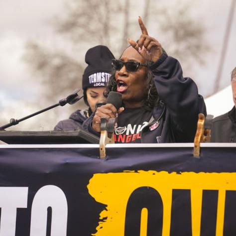 People speaking into microphones at rally. 