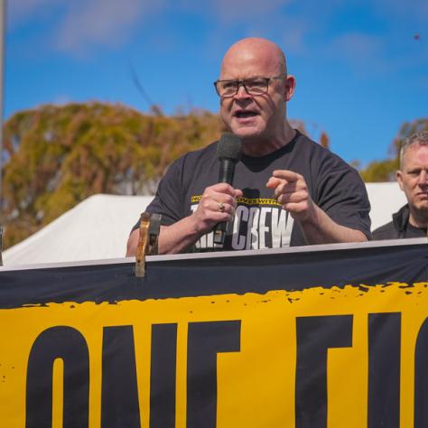 People speaking into microphones at rally. 