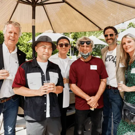 Group of people posing under an umbrella outside. 