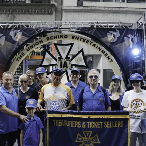 People at a parade posing with a banner. 