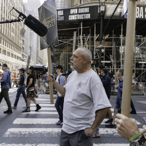 Man at parade speaking into mic. 