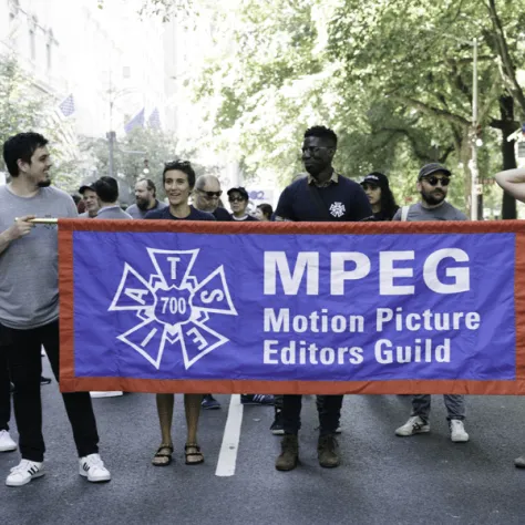 People marching in a parade with a banner. 