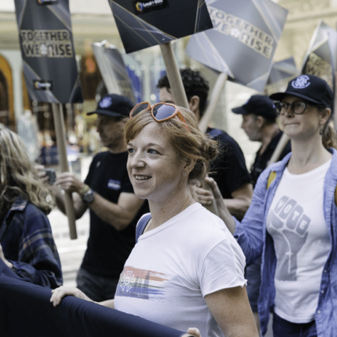 People marching in a parade with signs. 