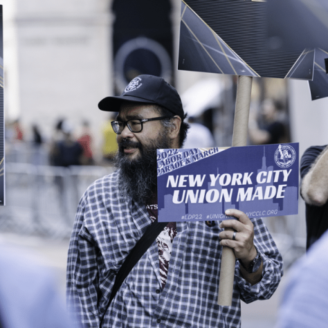 Man in a parade holding a sign. 