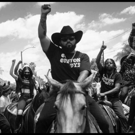 Man on a horse with fist in the air surrounded by people. 