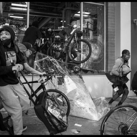 People taking bikes out of broken window. 