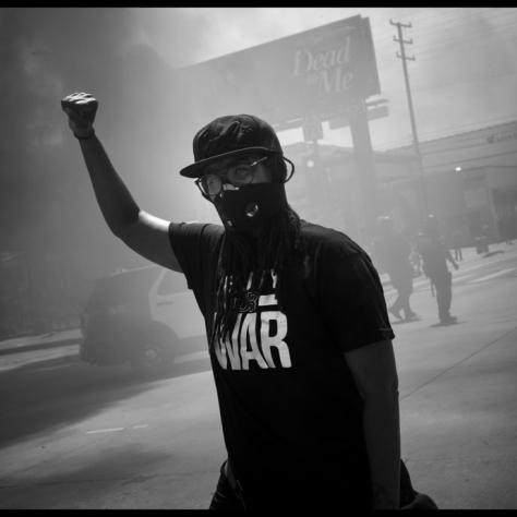 Man with fist in the air and smoke behind him. 