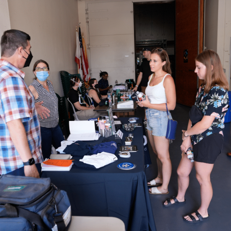 People talking to each other at an indoor yard sale. 