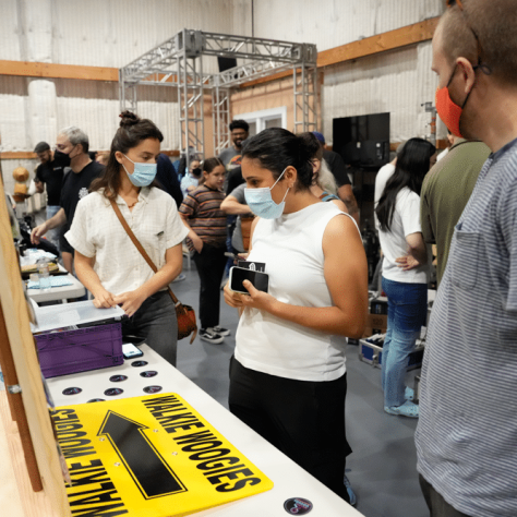 People talking to each other at an indoor yard sale. 