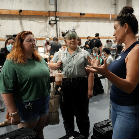 People talking to each other at an indoor yard sale. 