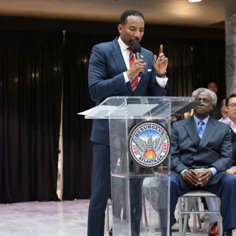 Man speaking in front of people at a podium. 