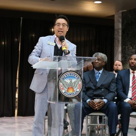 Man speaking in front of people at a podium. 