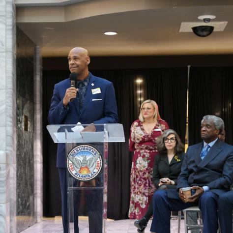 Man speaking in front of people at a podium. 