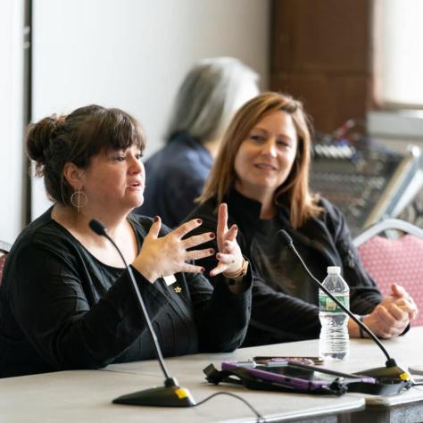 Woman speaking at a table. 