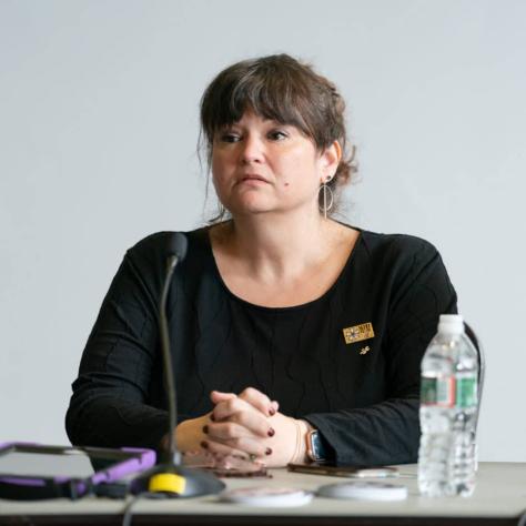 Woman speaking at a table. 