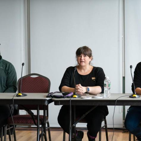 People sitting at the front of the room with mics. 