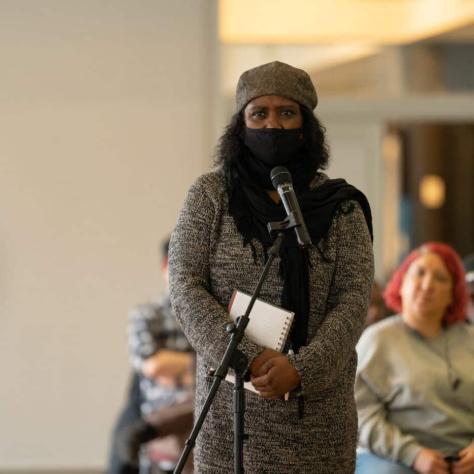 Woman standing and speaking into mic. 