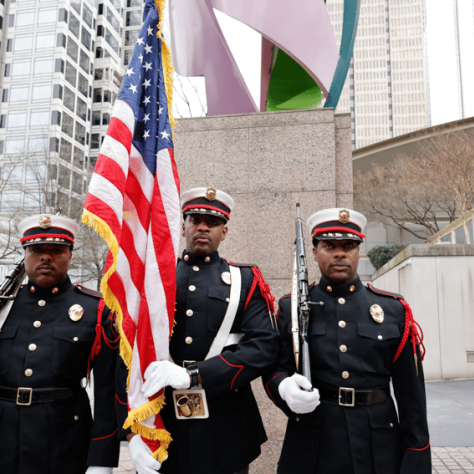 Military members holding American flag. 