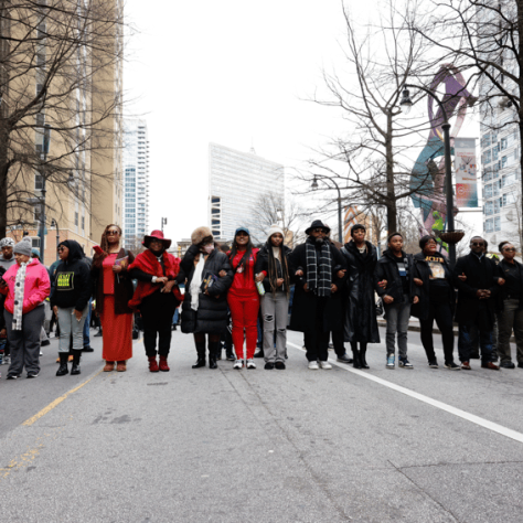 Line of people marching down the street. 