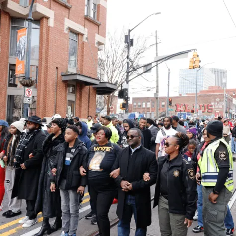 Group of people walking in line down the street. 