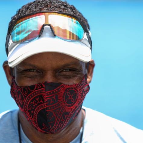 Close up of man with white hat and sunglasses and red and black mask. 