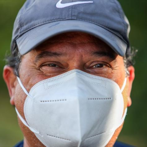 Close up of man in hat wearing white mask. 