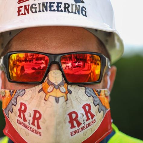 Close up of man in Engineering hat and white and red mask. 