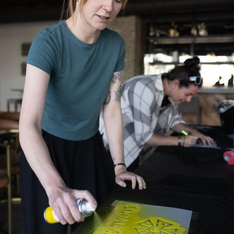 Woman using spray paint and stencil. 